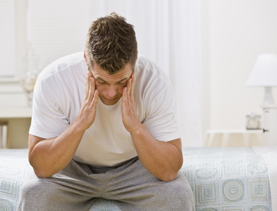 Tired Man Sitting on Bed